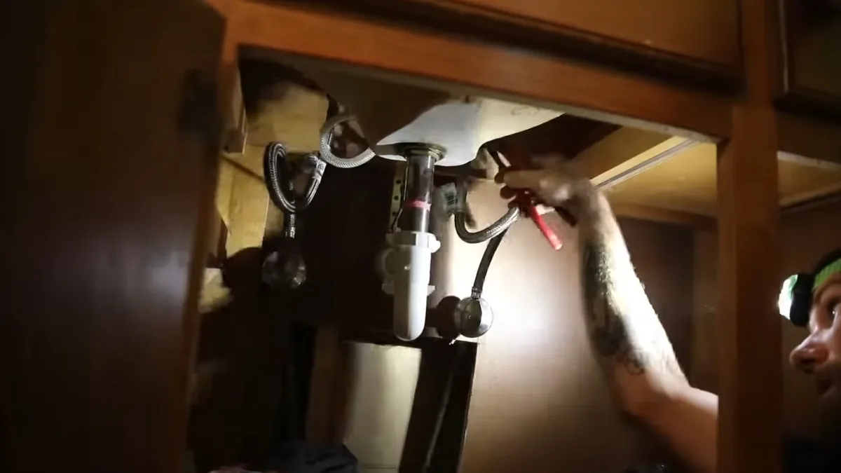 Plumber working on a repair under a sink cabinet