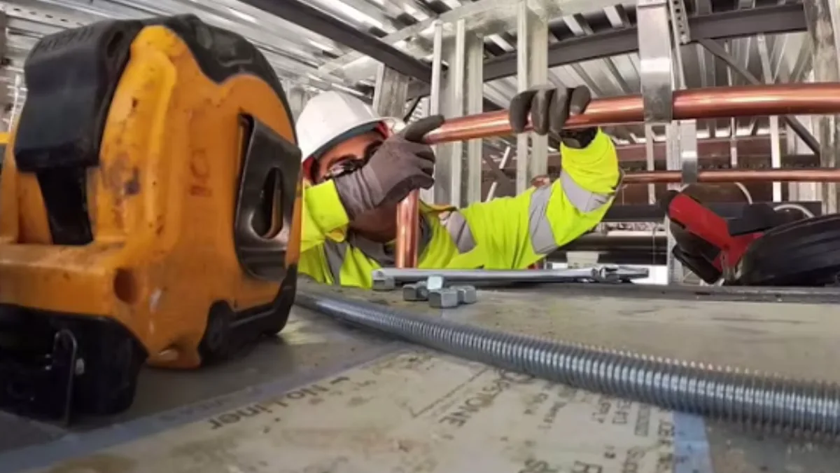 Technician installing overhead copper piping in a commercial building
