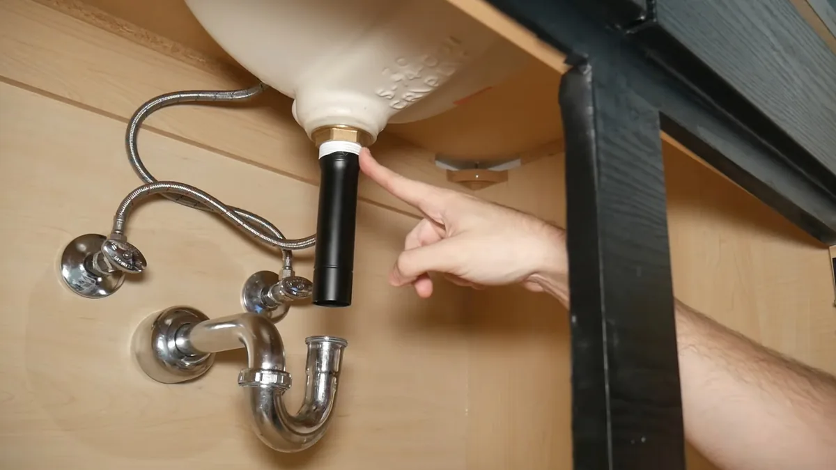 Technician inspecting an under-sink connection for a hidden leak