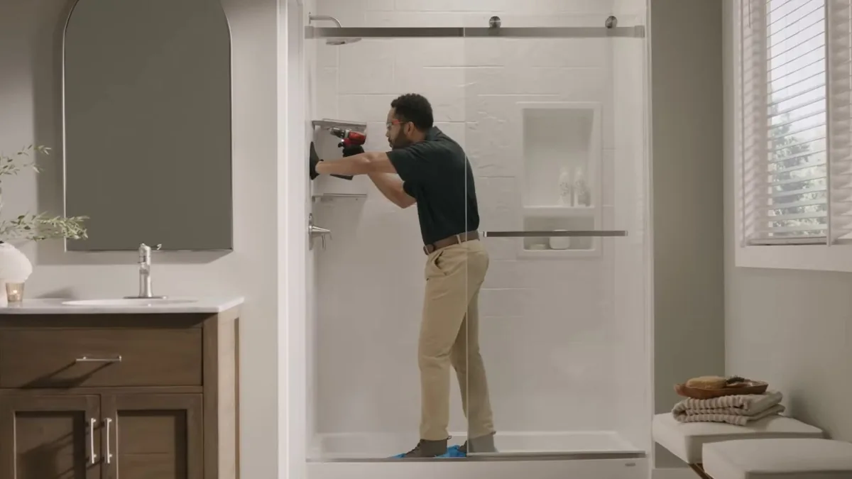 Technician installing a glass shower door and surround