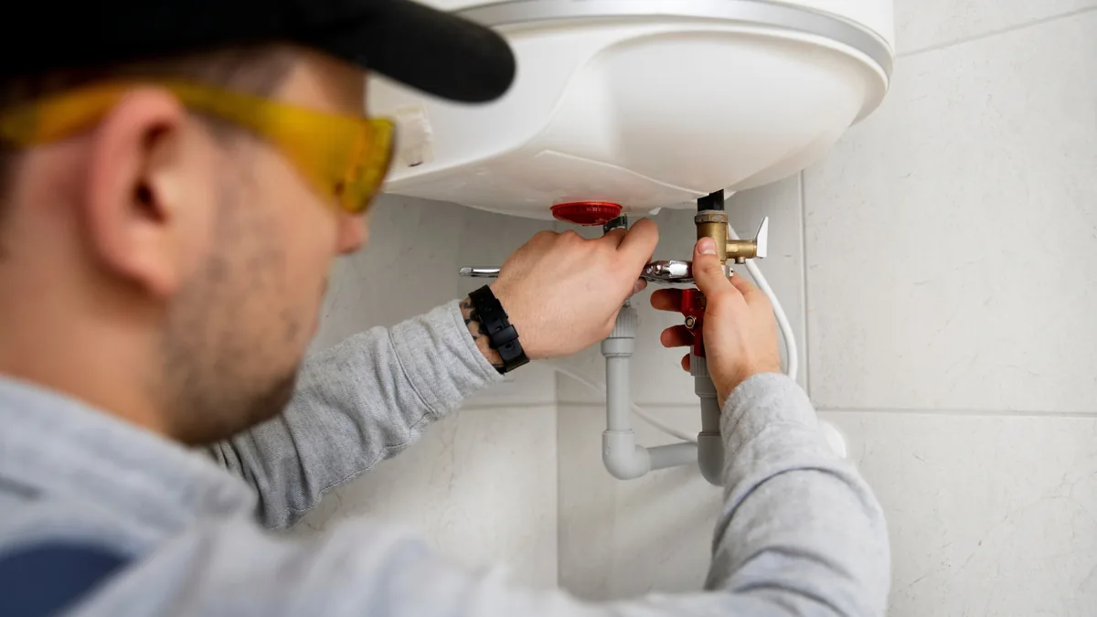 Technician repairing a water heater's supply valve connections
